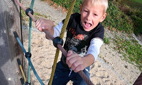 fröhlicher Junge beim klettern