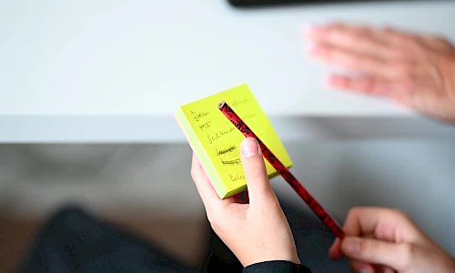 Hände mit Zettel und Stift